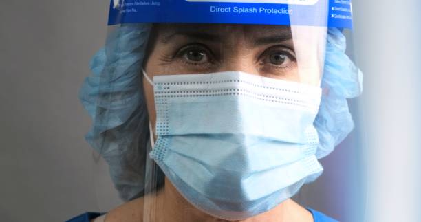 istock Tired, overworked, exhausted health care worker wearing a mask and a face shield posing looking at the camera 1258024171