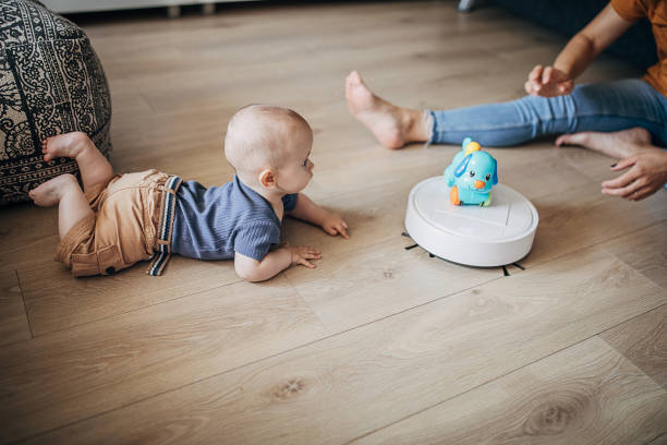 istock Mother and her baby boy playing while robotic vacuum cleaner cleaning 1258024181