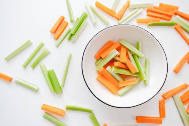 istock Sliced carrots and celery in a white bowl, healthy food background 1258024235