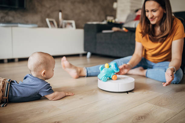 istock Cheerful mother playing with her little boy while robotic vacuum cleaner cleaning 1258024946