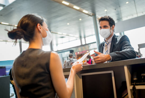 Traveling business man doing the check-in at the airport wearing a facemask Portrait of a traveling business man doing the check-in at the airport wearing a facemask during the COVID-19 pandemic â travel concepts airport check in counter photos stock pictures, royalty-free photos & images