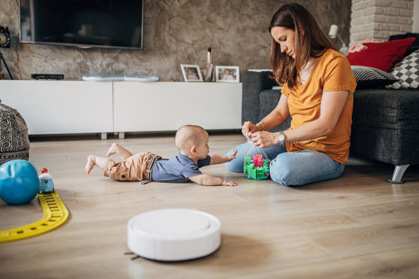 istock Beautiful mother playing with her little son while robotic vacuum cleaner cleaning 1258025156