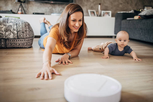 istock Beautiful mother playing with her little boy while robotic vacuum cleaner cleaning 1258025185