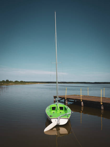 pequeno veleiro verde é anexado a um lago em um estágio de pouso - plank boardwalk pontoon bridge summer - fotografias e filmes do acervo