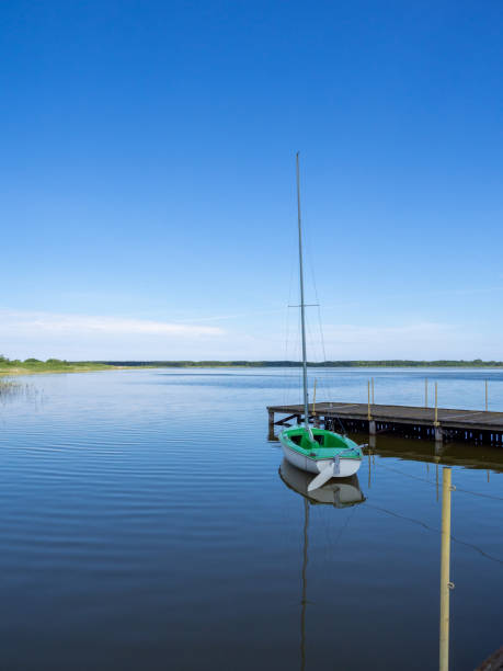 pequeno veleiro verde é anexado a um lago em um estágio de pouso - plank boardwalk pontoon bridge summer - fotografias e filmes do acervo