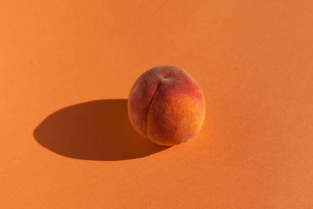 frischer pfirsich auf orangefarbenem hintergrund mit schatten, horizontale ausrichtung mit kopierraum - nectarine peaches peach abstract stock-fotos und bilder