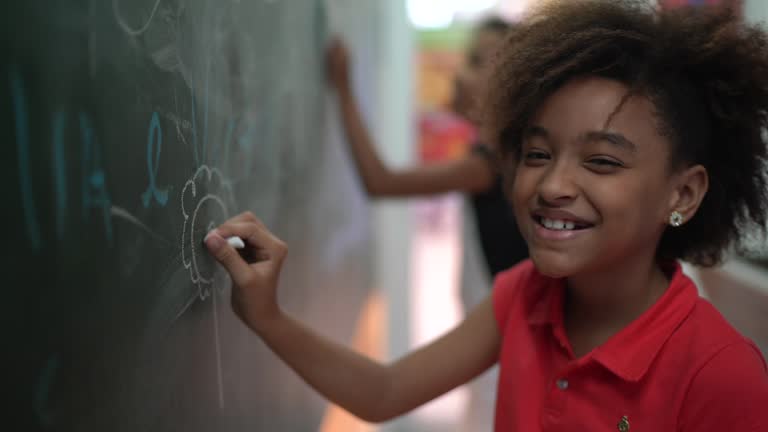 Portrait of young girl drawing in blackboard at home