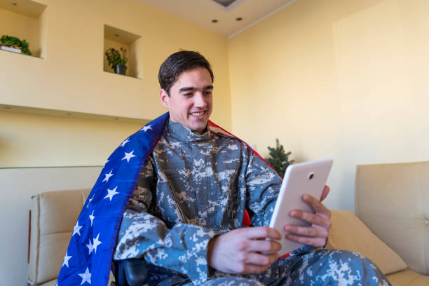 Young War Veteran is Communicating over the Digital Tablet and Holding a US Flag