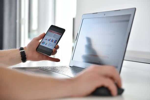 istock Hands of businessman using cellphone at blurry office table with financial chart 1258038911