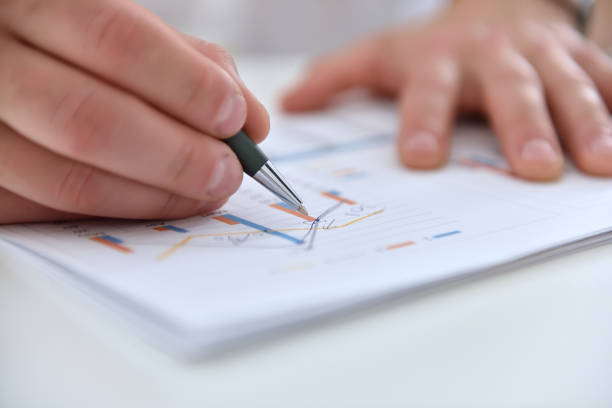 istock Businessman hands analyzing financial report and statistics 1258038919