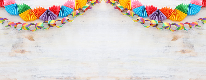 Paper colorful chain garland over white wooden background. Traditional jewish sukkot holiday decoration