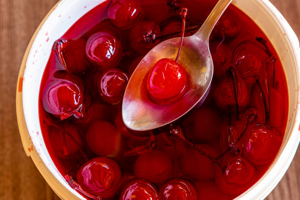 Spoon picking up pickled cherry in a full bucket