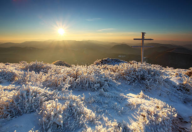 Silhouettes of crucifix symbol with bright sunbeam on the colorful sky background