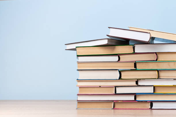 istock A large stack of books stands on a wooden table against a light blue wall, space for text 1258065821