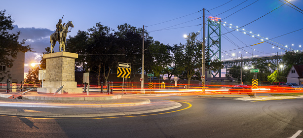Windsor, Ontario, Canada - July 24, 2020:  Sandwich town is one of Ontario's oldest towns and was the site of many historic battles in the past, especially with respect to the War of 1812.   This photo depicts a turning circle (traffic circle) overlooking the Ambassador Bridge (which links Windsor with Detroit, Michigan).   The statue on the left of the frame depicts two famous historical figures related to the War of 1812.  On the horse is Chief Tecumseh, a local native leader and not seen behind the horse, standing, is General Isaac Brock who commanded the local British troops fighting against the American forces.  The alliance of Chief Tecumseh and General Brock was instrumental in fighting off the Americans from this site and preserving the Canadian border as it stands today.
