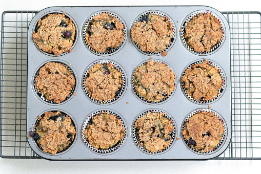 Tray of hot blueberry muffins cooling on kitchen counter