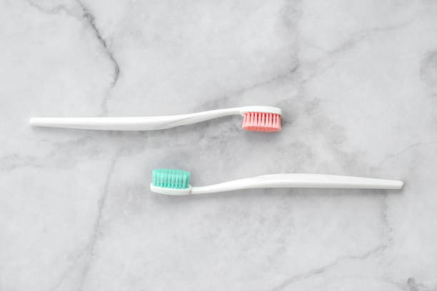 zwei zahnbürsten mit rosa und türkisblau borste auf marmorhintergrund. dental- und gesundheitskonzept. ansicht von oben, flach liegend. - toothbrush pink turquoise blue stock-fotos und bilder