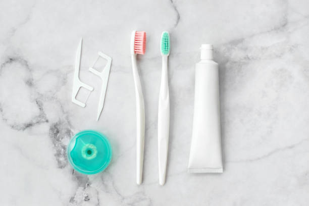 istock Set of pink and turquoise blue toothbrushes, toothpaste and other tools on marble background. Dental and health care concept. Top view, flat lay. 1258073984