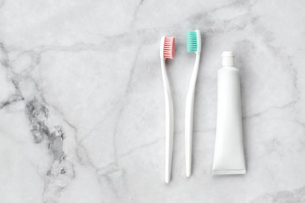 zwei zahnbürsten mit rosa und türkisblau borste und zahnpasta auf marmorhintergrund. dental- und gesundheitskonzept. ansicht von oben, flach liegend. freier kopierbereich. - toothbrush pink turquoise blue stock-fotos und bilder