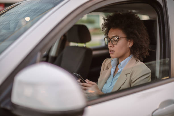 istock Business woman using smart phone in a car 1258074683