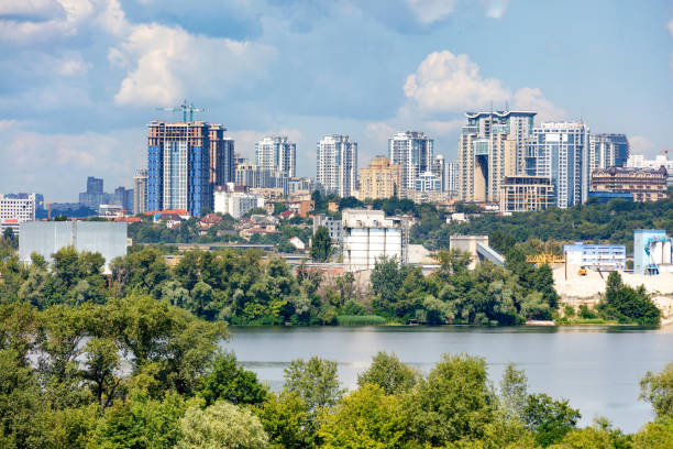 New high-rise buildings are being built on the river bank. Construction of new high-rise buildings on the right bank of the Dnipro River in Kyiv, a view of the facades of multi-storey residential buildings among private houses and a blue cloudy sky, copy space. dnipropetrovsk stock pictures, royalty-free photos & images