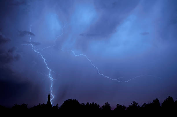 дождь падения и инсульта раздвоенные молнии во время грозы ночью над церковью башни и деревья - german culture flash стоковые фото и изображения
