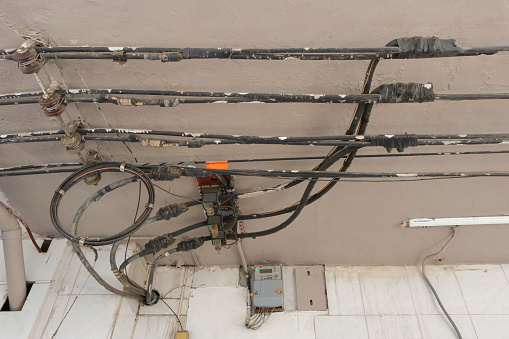 Tapping 3-phase 4-wire power lines run on ceiling of canopy by using electrical tapes, then the cables installed in a pipe run through the wall of the building, power distribution concept, selective focus