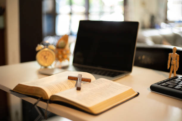 istock Cross over wood table with window light. online church concept. 1258083433