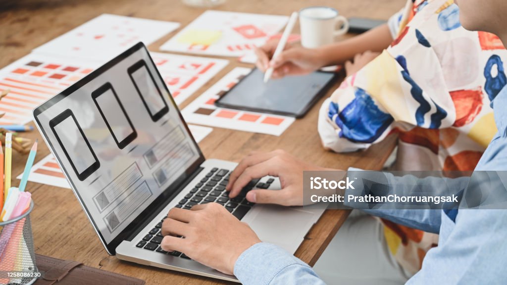 Abgeschnittenes Bild von zwei Personen verwendet einen Computer-Laptop mit einem Interface-Symbol auf dem Bildschirm am Holztisch. - Lizenzfrei Webdesign Stock-Foto
