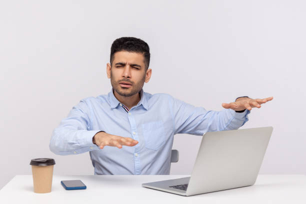 istock Blind disoriented man employee sitting office workplace, outstretching hands trying to find laptop on desk 1258086420