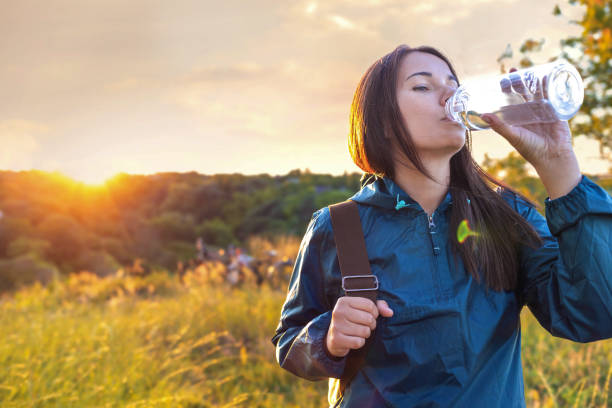 Young woman practicing healthy lifestyle drinking water sunset