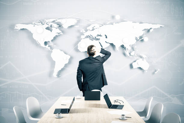 istock Pensive businessman looking on airline route on world map on wall. 1258093607