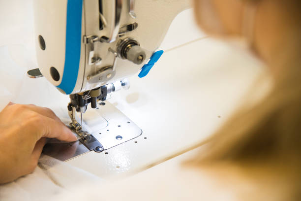 istock Woman hands with fabric at sewing machine 1258095048
