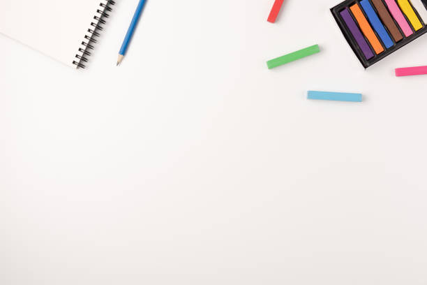 istock Colored wax crayons, sketchbook isolated on white background. Colorful chalk. Flat lay, top view, copy space. 1258096082