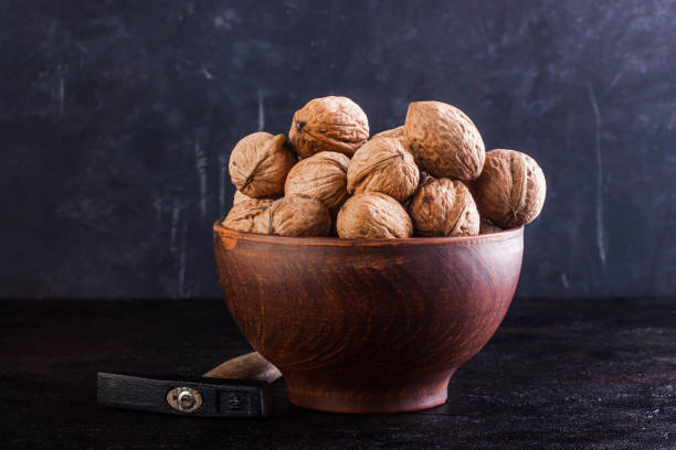 istock Walnut in a clay bowl and a gout on a concrete background 1258097822