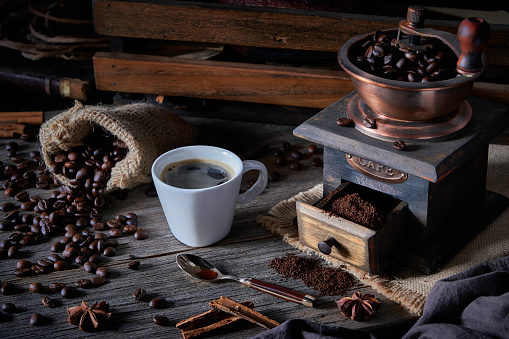 Espresso coffee cup and grinder on vintage table and roasted coffee beans in a burlap