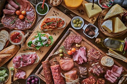 Tapas of cheese, cured ham, salami, wine and chorizo on a rustic wooden table