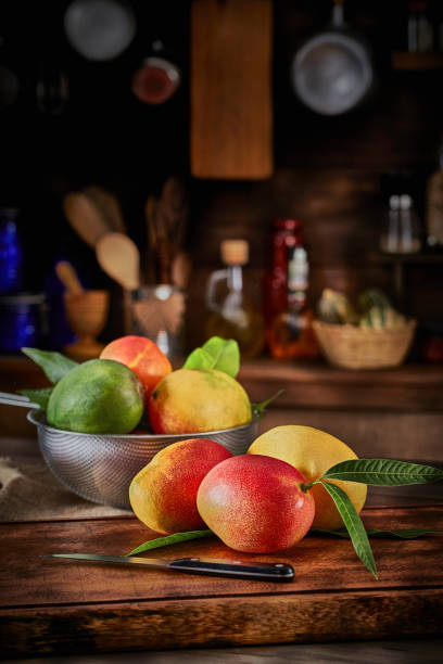 istock Tropical fruits. Group of ripe mangos on a table in a rustic kitchen 1258104976