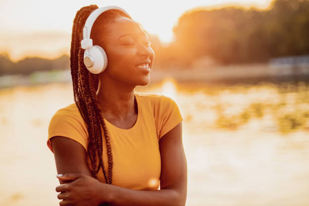 mujer afroamericana moderna se relaja junto al río - arms crossed audio fotografías e imágenes de stock