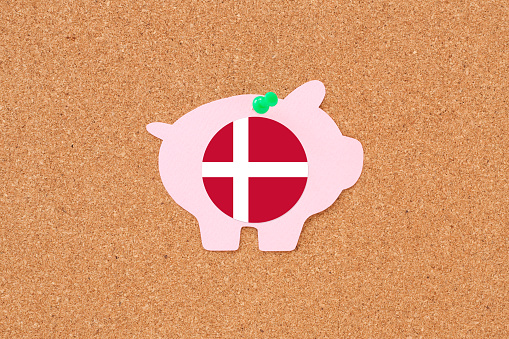 Paper piggy bank with danish flag hanging from cork board