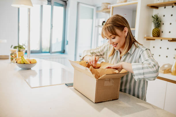 młoda kobieta rozpakować paczkę zamówiła online - dom shopping zdjęcia i obrazy z banku zdjęć