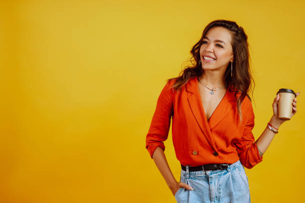 istock Young woman with coffee posing on yellow background. 1258110061