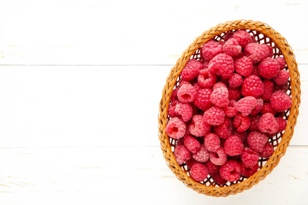 istock Fresh raspberry in a basket on white wooden background 1258112550