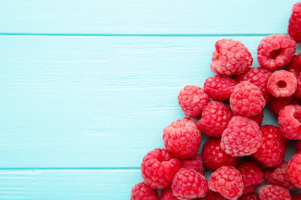 istock Ripe raspberries on blue wooden background with copy space. 1258112627