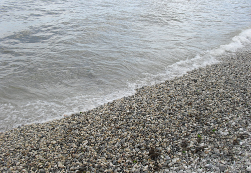 sea wave with foam on the shore with pebbles. background, banner, summer travel