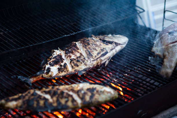 Large fresh fish from the sea grilling on the barbecue outdoors closeup