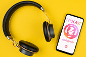 bove view of headphones and smartphone playing podcast on yellow background