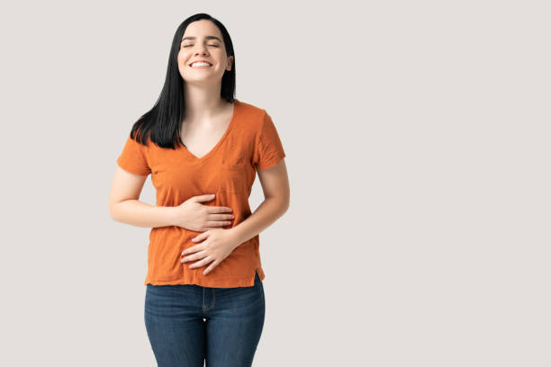 mujer caucásica manteniendo ambas manos en el vientre - abdomen fotografías e imágenes de stock