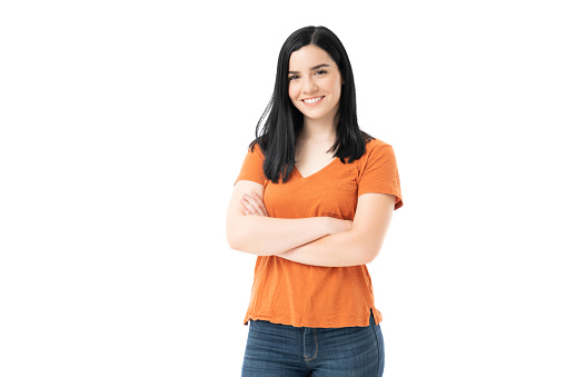 Smiling attractive young woman standing with arms crossed against white background