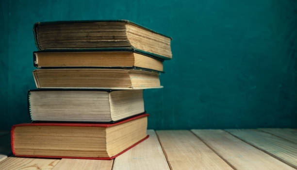 istock Old books on a old wooden table. Beautiful green wall background. 1258125546